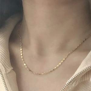 Close-up of a minimalist gold-plated lace-style brass choker necklace on a model