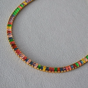 Collier tennis en zircons multicolores coupe baguette et plaqué or sur fond gris
