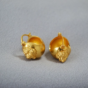 Detailed close-up of a 3D tiger head relief on a golden brass dome hoop earring