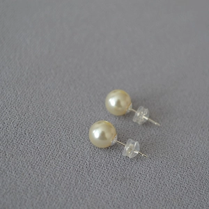 Macro shot of large high-luster faux pearl studs with silver pins and silicone backs