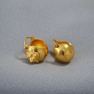 Macro detail of 3D sculpted gold brass lion head earrings with ornate relief patterns