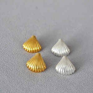 Detailed view of vintage shell stud earrings in gold and silver plating on fabric