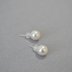 Macro shot of large faux pearls with 925 silver studs on grey textured surface