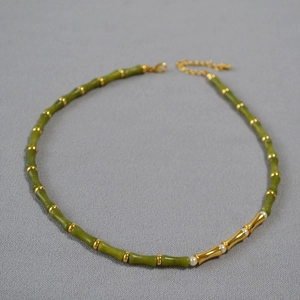 Detailed close-up of green bamboo bead necklace with golden metal accents and pearls