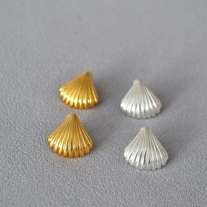 Macro detail of matte gold and silver seashell earrings with fine texture and s925 posts