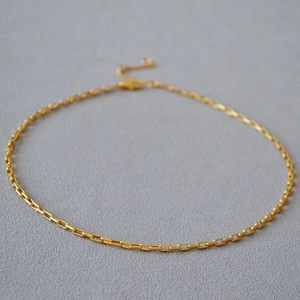 Détail d'un collier ras du cou en laiton doré minimaliste avec fermoir mousqueton réglable