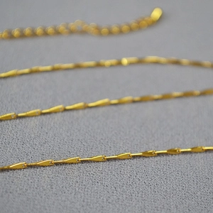 Macro shot of gold-plated brass minimalist chain necklace with sleek water drop links