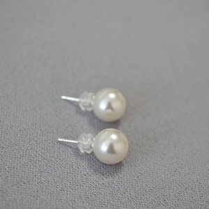 Macro view of round faux pearl earrings with 925 silver posts and silicone backs