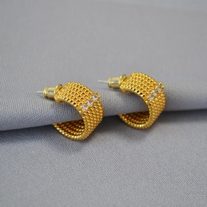 Detailaufnahme goldener C-förmiger Ohrringe mit gedrehter Textur und weißen Zirkonia