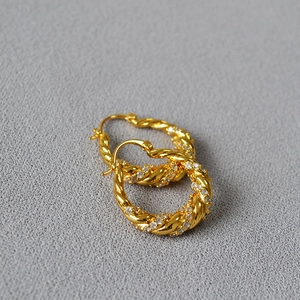 Gold twist hoop earrings with micro-set sparkling zircons in a minimalist luxury style