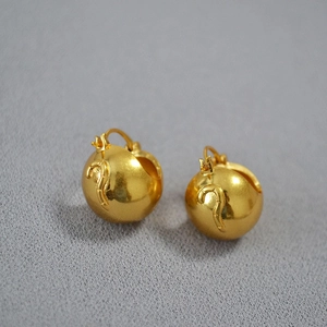Macro detail of vintage 3D tiger head brass earrings with intricate golden relief texture