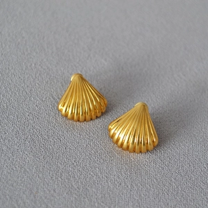 Macro detail of gold-plated shell earrings showing elegant radial metal texture