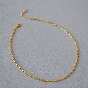Détail d'une chaîne trombone dorée avec fermoir mousqueton et pendentif coeur