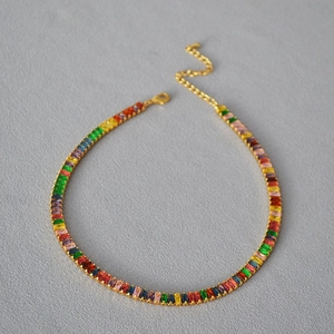 Vue détaillée des pierres de zircone arc-en-ciel sur un collier choker doré brillant
