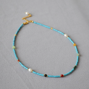 Close-up of bohemian beaded necklace with turquoise stones and freshwater pearls