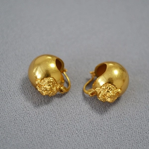 Detailed macro view of vintage brass lion head relief on golden earrings with textured finish
