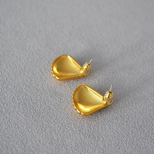 Macro detail of gold-plated shell-shaped earrings showing secure bullet clutch backings