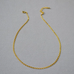 Close-up of gold-plated brass chain with oval lace links and lobster clasp detail