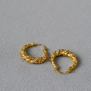 Gold twisted hoop earrings with shimmering white zircons in a minimalist spiral design