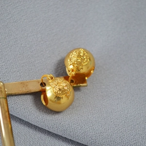 Macro shot of 18k gold plated brass tiger head relief earrings on a metal display stand