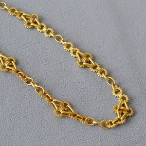 Détails des anneaux en forme d'engrenage et maillons géométriques sur collier doré
