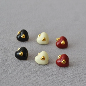 Detail of heart stud earrings set in black, cream and red enamel with gold accents