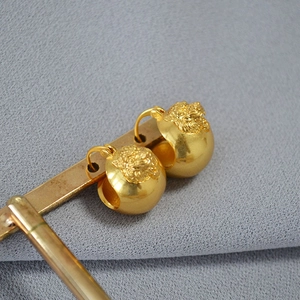 Close-up of vintage brass tiger head relief on golden sphere earrings displayed on stand