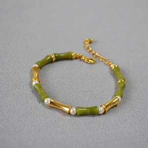 Close-up of green bamboo-shaped jade beads with gold accents and small white pearls
