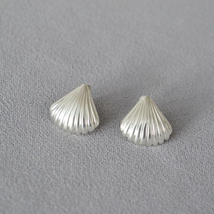 Silver shell shaped earrings with radial texture on minimalist grey fabric background