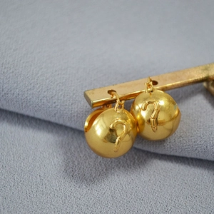 Detailed view of gold-plated spherical earrings featuring embossed question mark motifs
