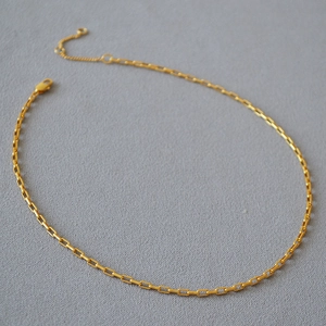 Vue macro d'un collier chaîne trombone dorée minimaliste avec fermoir réglable