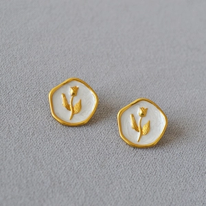 Détail de boucles d'oreilles en laiton doré avec émail blanc et relief de tulipe