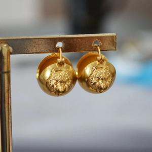 Detail view of 3D brass tiger head earrings with vintage gold-plated finish
