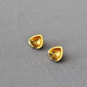 Macro view of gold heart earrings back detail with silver needle posts and metal backs