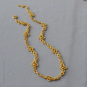 Détail des engrenages en laiton doré et maillons géométriques sur un collier long