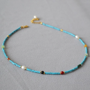 Close-up of vintage beaded necklace with turquoise tubes, pearls and gold lobster clasp