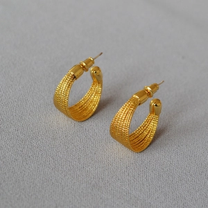 Macro shot of gold-plated woven texture hoop earrings with intricate mesh pattern