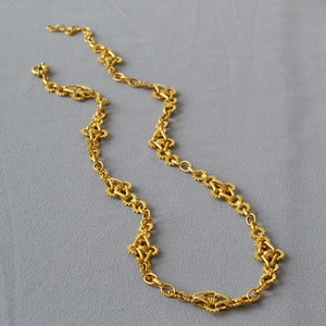 Collier à maillons d'engrenage doré au style industriel sur fond de tissu gris