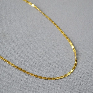 Close-up of vintage gold-plated brass chain with textured oval lace-style links