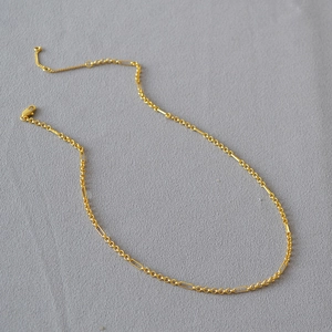 Detail of gold-plated brass chain with interlocking links and lobster clasp closure