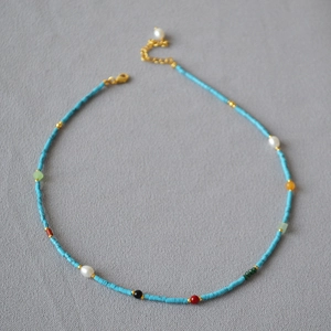 Detail of beaded necklace with blue turquoise tubes, pearls and gold lobster clasp