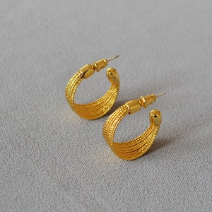 Detailed view of gold C-shaped earrings featuring a multi-layered woven wire texture