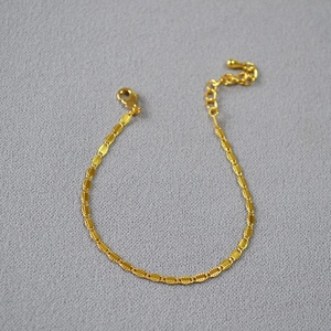 Detail of gold brass lace chain necklace with textured oval links and lobster clasp