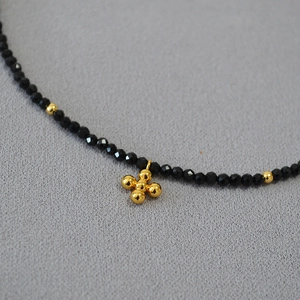 Elegante girocollo di perle nere di spinello con perle d'oro e ciondolo a croce