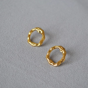 Macro detail of irregular wavy gold earrings with polished mirror finish and texture