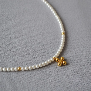 Elegant pearl choker necklace with gold cross pendant and beads on grey background