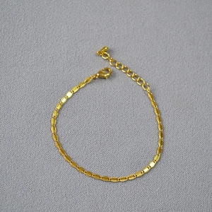 Close-up of gold plated brass chain with lobster clasp and teardrop pendant detail