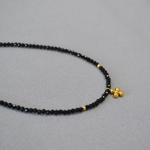 Collana girocollo in spinello nero con ciondolo a croce dorata per donna