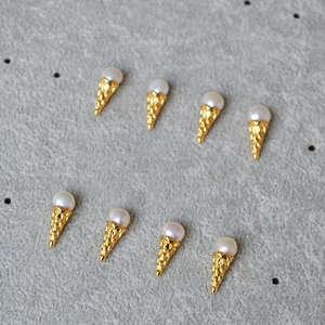 Detailed view of eight ice cream cone pearl earrings arranged on a stone surface