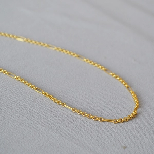 Macro shot of gold plated brass necklace with intertwined rings and rectangular tube links